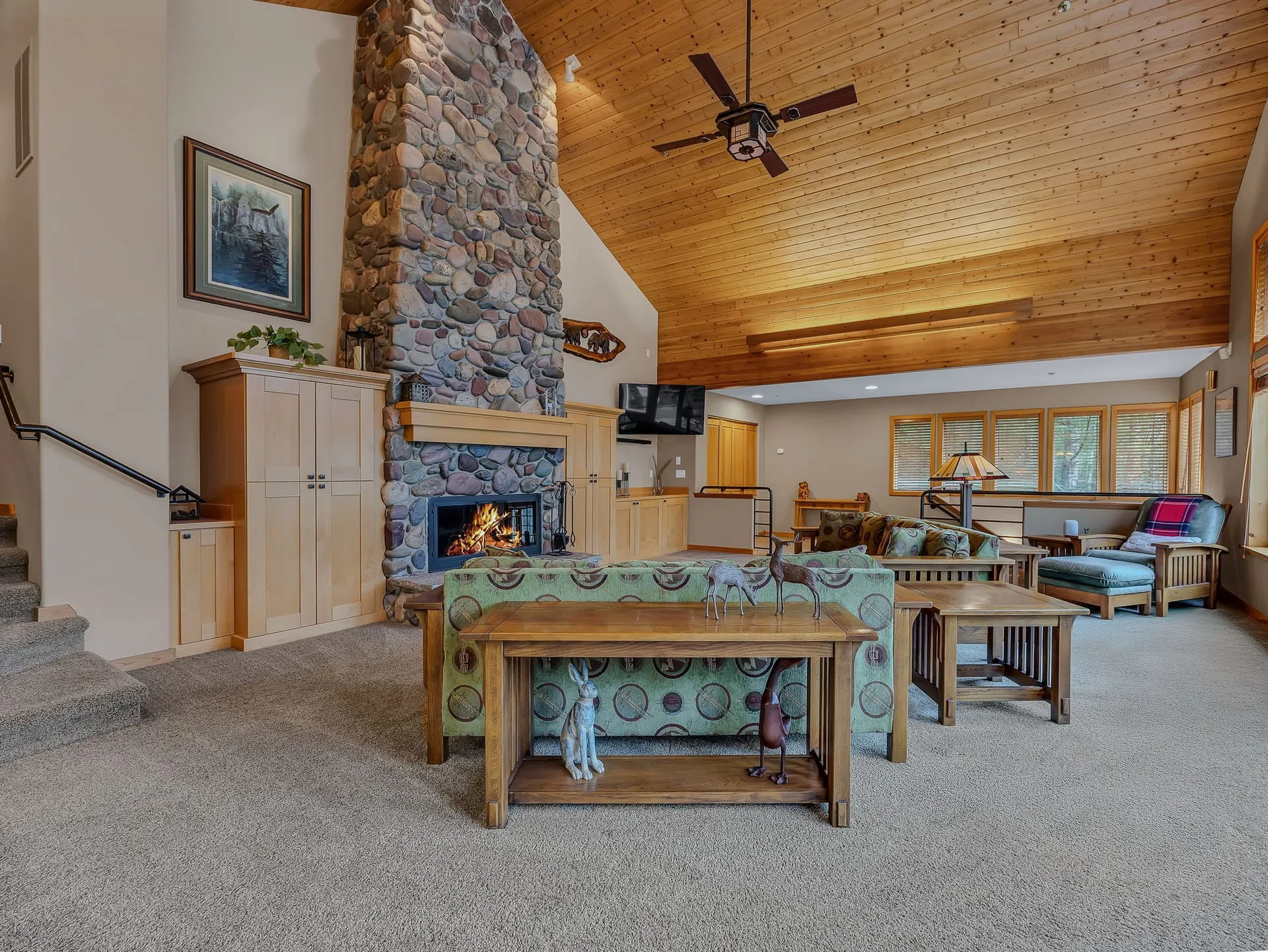 Vaulted great room with a wood ceiling and floor-to-ceiling river rock fireplace
