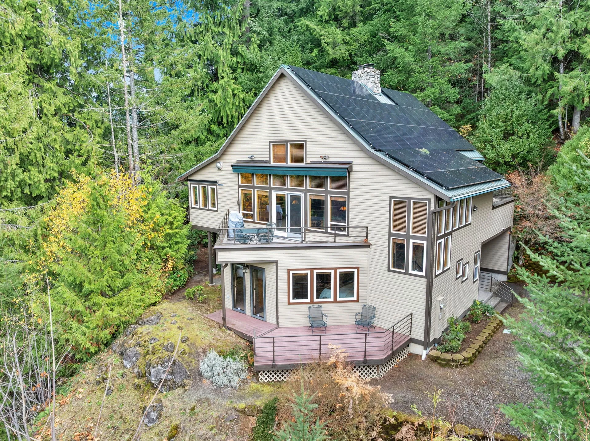Back of the home with decks on each level, set among the trees